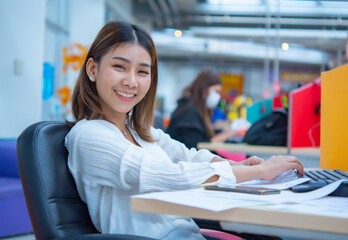 Beautiful asian business woman is sitting in her office, smiling and looking at the camera with happiness, Digital marketing.