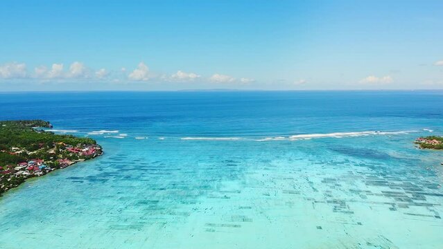 Idyyllic aerial view of underwater seaweed grass plantation fields. Aquaculture farm and white boats in clear shimmering water at bay in Nusa Lembongan, Selat Ceningan, Bali, view over ocean. 4K