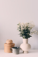 cozy home with minimalist bouquet, cup of coffee and boxes on white background.