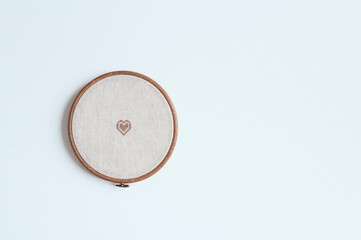 cross stitch embroidery accessories. Linen cloth in hoop on white background with copy space. Indoor hobby concept.