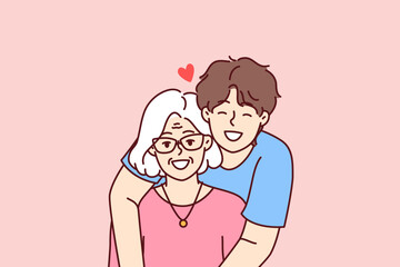 Noble guy teenager hugging elderly grandmother showing love and care for ancestors and communicating with family. Happy retired woman near caring son spending time in family atmosphere 