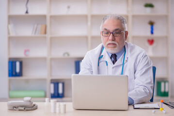 Old male doctor in telemedicine concept