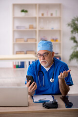 Old male doctor in telemedicine concept