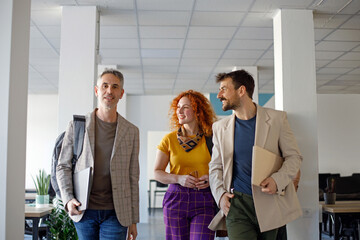 Coworkers talking while walking through corridor at office 