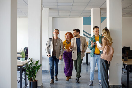 Coworkers talking while walking through corridor at office 
