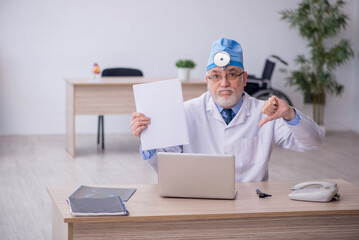 Old male docror otolaryngologist working in the clinic