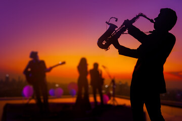 Silhouette saxophone musician man showing on blurry jazz trio band and sunset cityscape background. Double exposure process and copy space. - obrazy, fototapety, plakaty