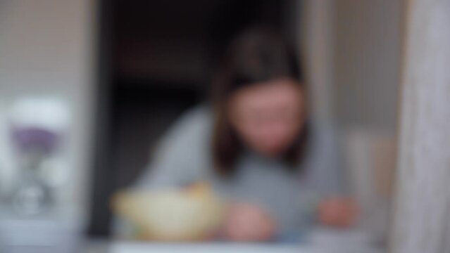 Girl eats in the kitchen at the table blurred background. Morning breakfast lunch, at home
