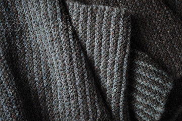 Knitted scarf folds, black and gray stripes. Dark knitted texture background.