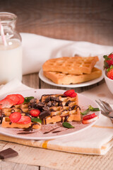 Waffles with strawberries and chocolate cream.