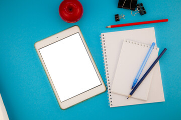 Tablet mockup blue background top view. Workplace copy space. Notepad, notebook, pen. Study and work planning. Self-learning. Online business course. Education remotely. Flatlay of blank screen tablet