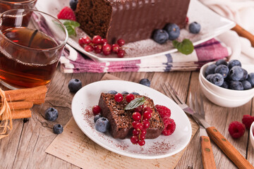 Chocolate sponge cake with fresh fruit on white dish.