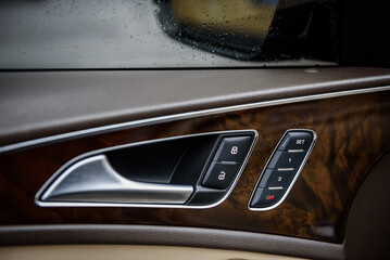 Obraz premium Car inside door chrome handle. Panel with seat settings driver's. Buttons to adjust driver's seat memory. Closeup car interior. Car door control left panel. Blocking opening and closing of doors.