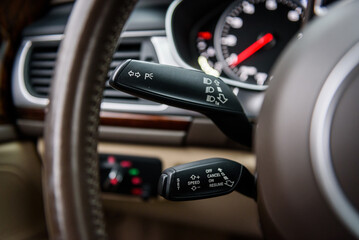 Cruise control, control of headlights and turns. Helm of car, steering wheel close up. Modern interior in an expensive complete set. Car interior from the inside. Closeup details.