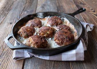Meatballs in a hot fying pan isolated on wooden table