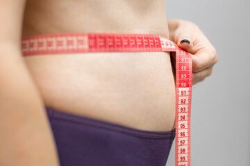 woman measuring her waist with a measuring tape
