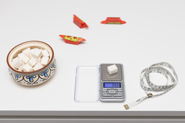 a sugar cube lies on a small scale.