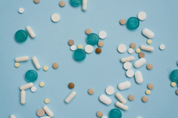 Tablets in bulk are multicolored on a blue background. The concept of medicine, pharmacy.