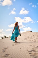 Beautiful blonde woman on hot sand with blue sky in the background. Photo taken on the shifting...