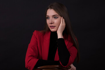 Portrait of a businesswoman in a red suit on a black background.