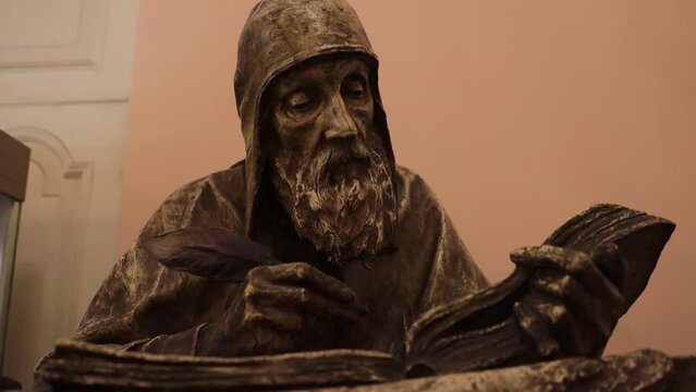 Russia Saint Petersburg 03.03.2023 Statue of a monk writing with a pen in a book