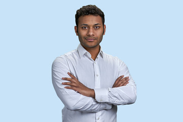 Portrait of brown asian businessman with folded arms. Isolated on pastel blue background.