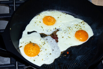 fried eggs with spices in a frying pan.