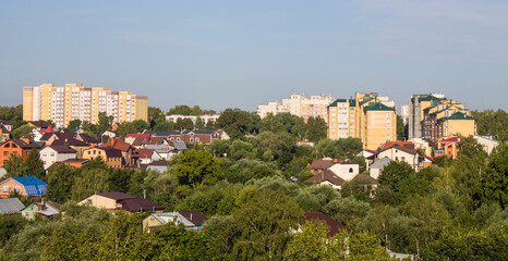 Obraz premium Panoramic top view of the modern houses of the residential area of the city of Vladimir in Russia and a park with lush green foliage of trees on a sunny summer day