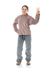 Full-length portrait of happy child  shows v-sign symbol of peace with fingers isolated on white background. Twelve year old girl doing victory sign and smiling to the camera in studio.