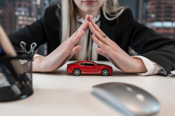 Business woman doing insurance on vehicle, holding red toy car on desk at office