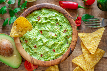 Guacamole, guacamole ingredients and chips on wooden background. Flat lay.