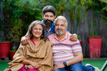 Indian senior couple sitting at outdoor with young man