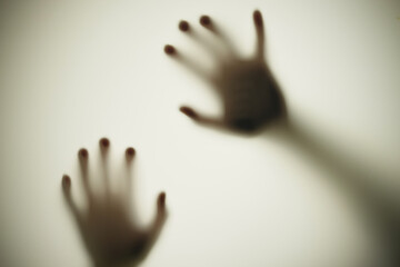 Blurred shadows of hands behind frosted glass, concept of nightmares, horror, domestic violence