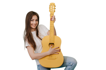 Cheerful young girl laughs, plays a yellow guitar on a transparent background in the studio, dressed in a white T-shirt and blue jeans, rocknroll mood. Mockup, party time, celebrating, happy people.