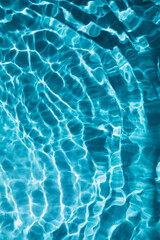 Abstract nature textured background, water waves in the pool with sun reflection, clear blue water