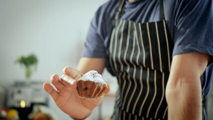 The pastry chef puts a gorgeous cupcake on a plate of perfect cupcakes sprinkled with powdered sugar. Appetizing footage with dessert