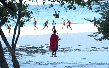 A maasai (Tanzanian national dressed man) watching African men playing football