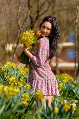 A  beautiful woman in a garden with yellow snowdrops on a spring day.