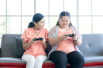 Fototapeta na wymiar Asian mother and daughter playing video games together at home. Home leisure lifestyle.