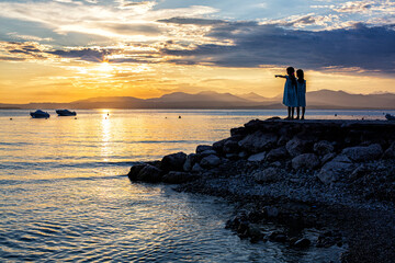 A beautiful golden sunset on the lake Garda, Italy. Silhouette of two girls looking at the sunset...