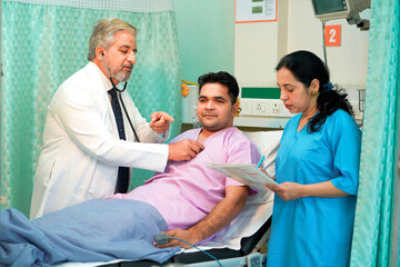 Senior Doctor check up using a stethoscope to patient on bed at hospital.