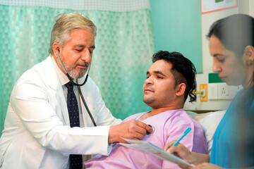Senior Doctor check up using a stethoscope to patient on bed at hospital.