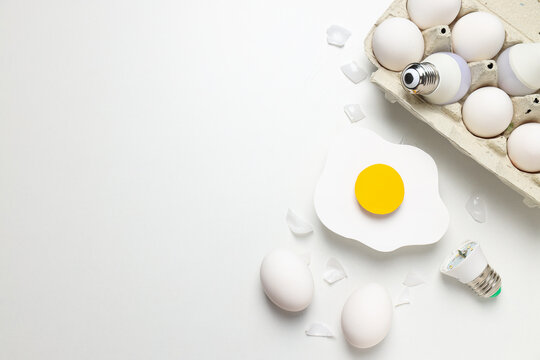 Eggs and bulbs on white background, space for text