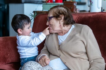 Little boy playing with his grandma on the couch