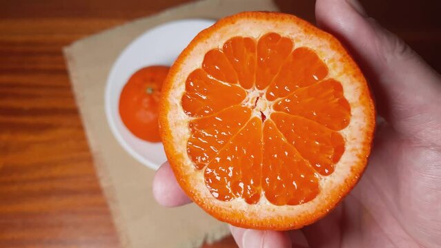 Tangerine cut across, in hand against other whole tangerines