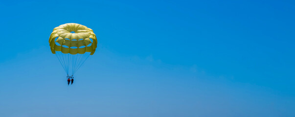 Parasailing on a yellow parachute against the blue sky. Beach extreme adventures. Background...