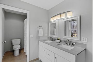a large white bathroom with two sinks and a toilet underneath it