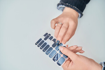 Close up view of a woman holding nail sticker decals. Manicure and beauty concept.