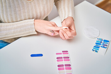 Woman applying nail decals to her nails on a table. Manicure and beauty concept.