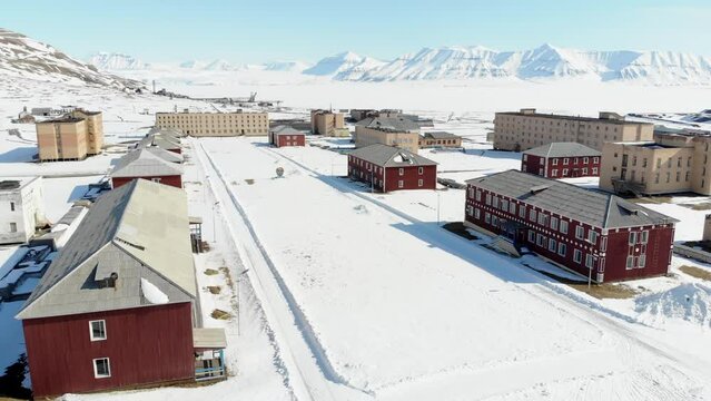Drone shot of the snow covering the houses, road and mountains of Pyramiden town in Spitsbergen